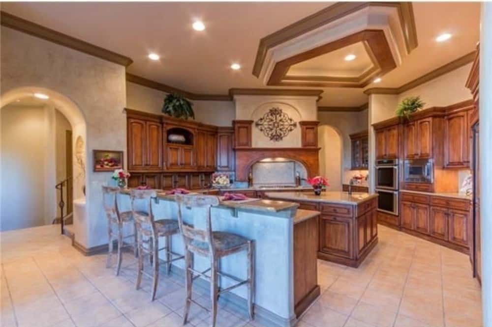 Kitchen with natural wood cabinetry, a center island, and a peninsula with a raised eating bar lined with cushioned counter chairs.