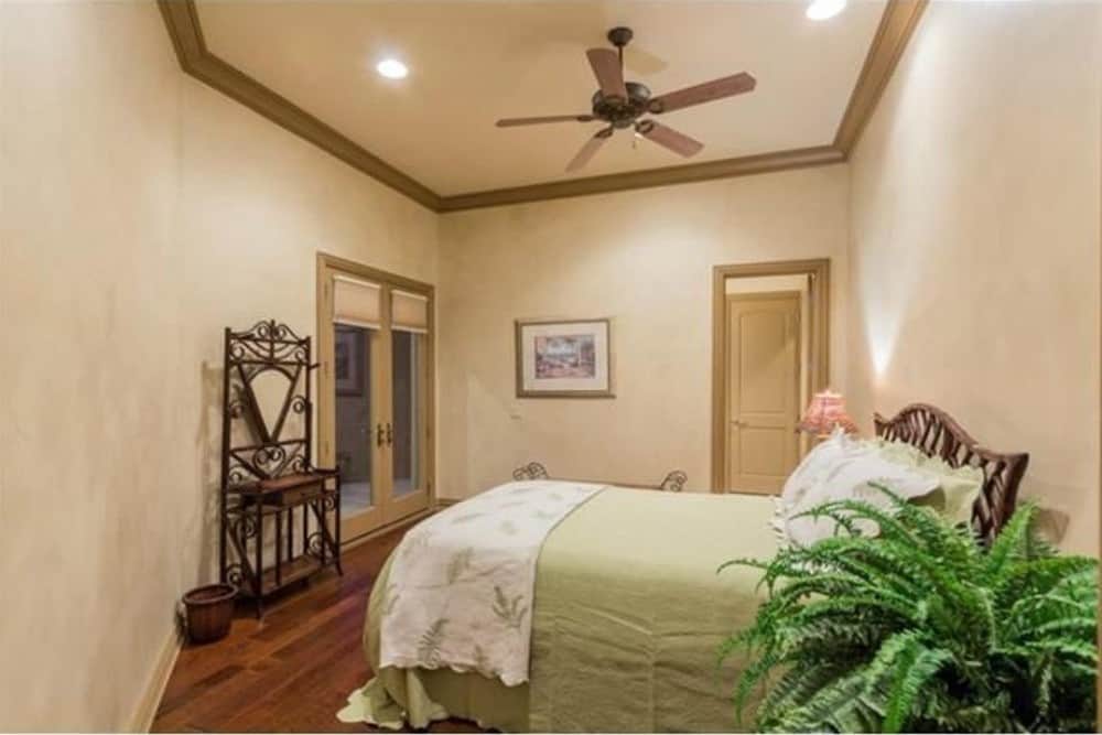 This bedroom offers a cozy wooden bed, ornate iron shelving, and private access to a covered porch via a french door.