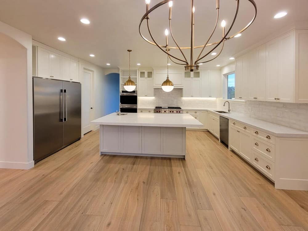 Kitchen with ample counter space, white cabinetry, and a large center island topped with glass globe pendants.