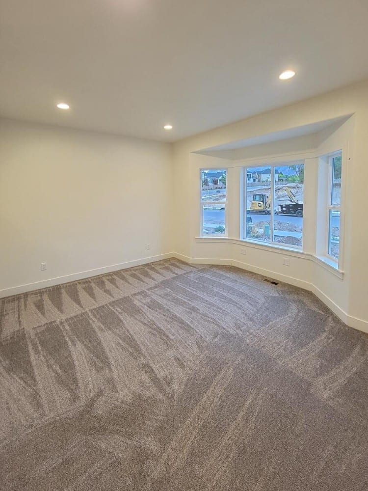 Home office with carpet flooring and a bay window that invites natural light in.
