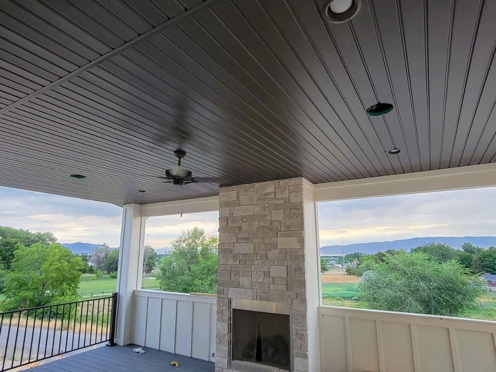 The covered deck includes a stone fireplace and paneled ceiling. It has a great view of the surrounding landscape.