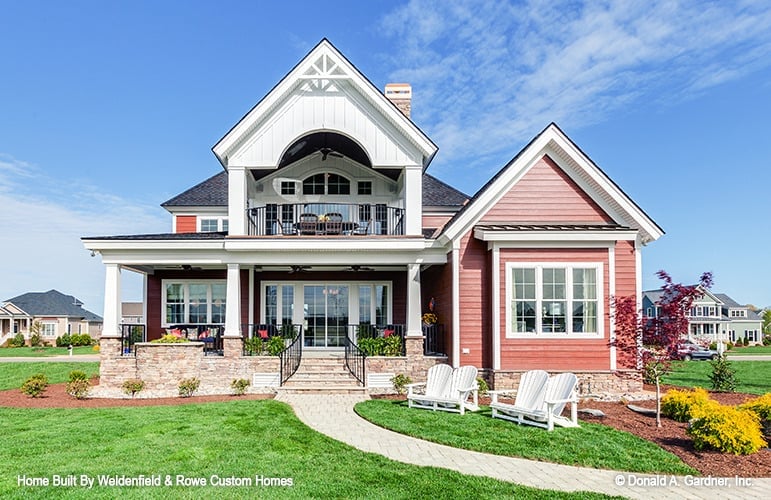 Rear exterior view with an upper balcony and a covered porch bordered with tapered columns.