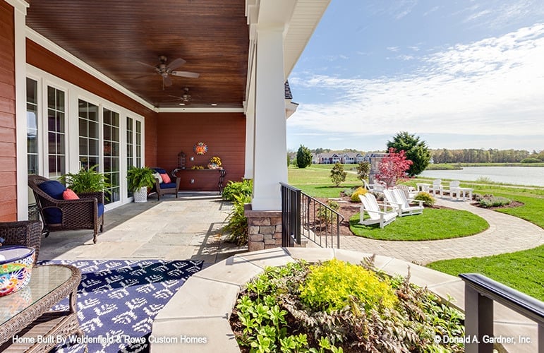 The covered porch transitions to an airy patio furnished with white loungers.