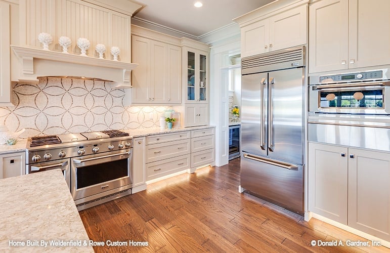 The kitchen offers cream cabinetry, stainless steel appliances, and a striking decorative tile backsplash.