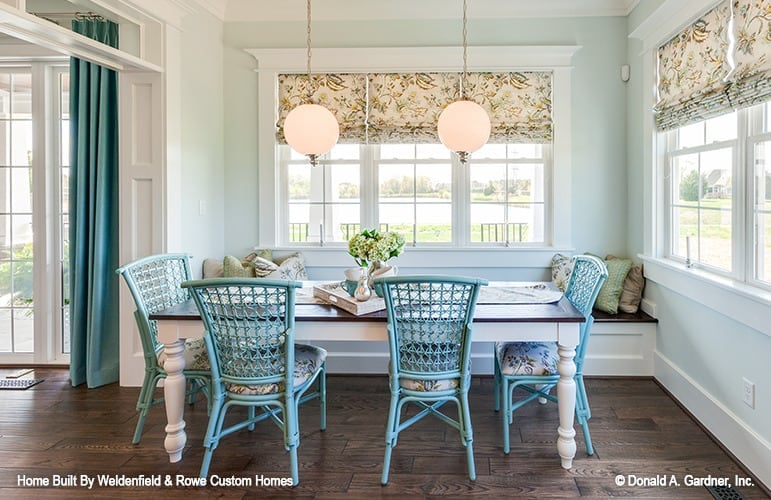 Breakfast nook with blue wicker chairs, a rectangular dining table, and a matching window seat.
