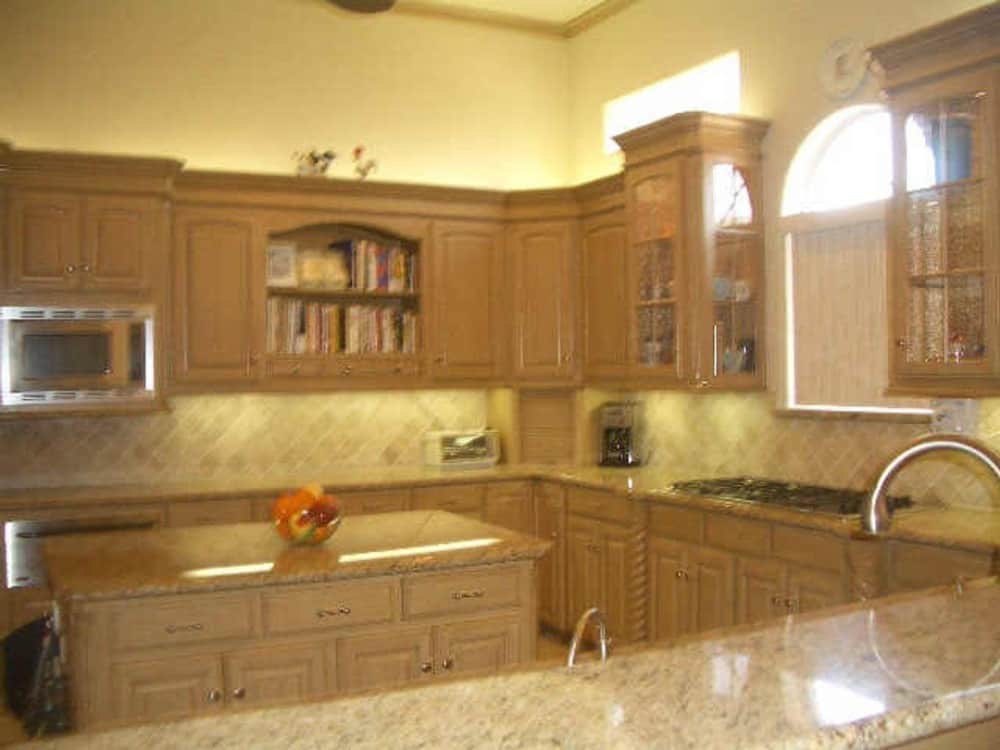The kitchen offers natural wood cabinetry, granite countertops, a center island, and a peninsula fitted with a sink.