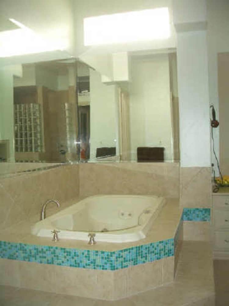 The primary bathroom features a deep soaking tub highlighted with blue mosaic tiles.