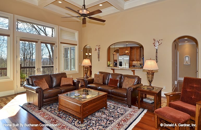 Great room with a coffered ceiling, leather sofas, glass too coffee tables, and a french door that opens to the rear porch.