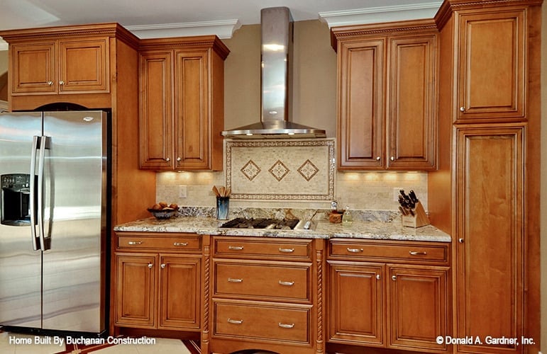 A built-in cooktop paired with a sleek vent hood completes the kitchen.