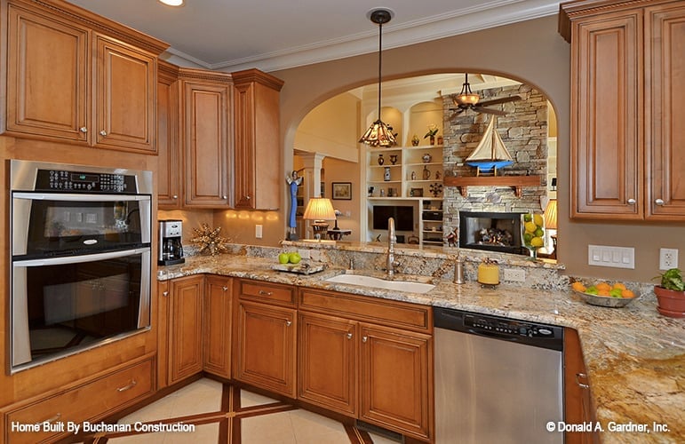 Kitchen wooden cabinetry, stainless steel appliances, and a serving bar framed with an open arch.