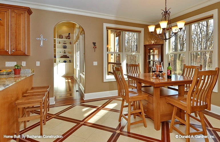 Breakfast nook with a wooden dining set, a warm chandelier, and white framed windows allowing natural light in.