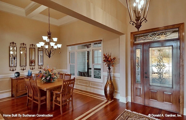 Formal dining room off the foyer with a 6-seater dining set, a matching buffet table, and beige walls graced with decorative mirrors and white wainscoting.