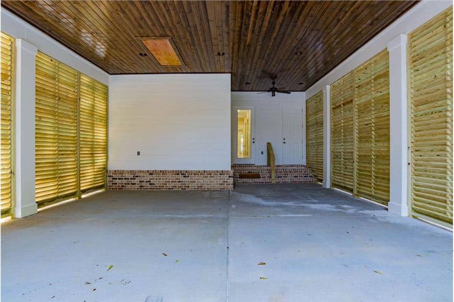 Carport with roller blinds, concrete flooring, and a wood plank ceiling.