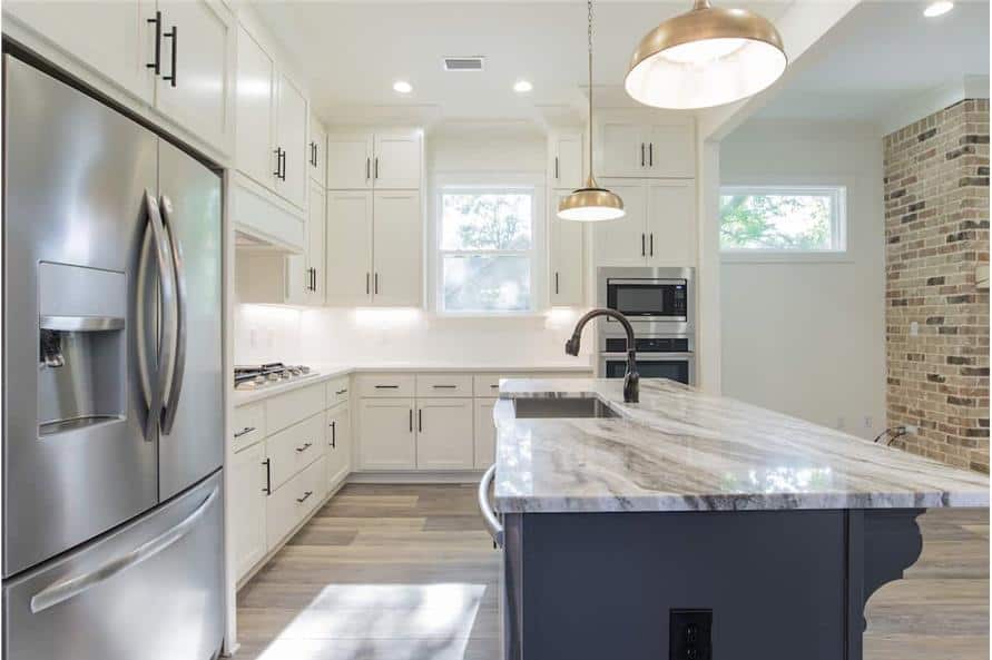 A closer look at the kitchen island fitted with a dishwasher, a sink, and a gooseneck faucet.