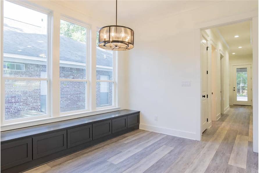 Dining room with a glass drum pendant and a built-in storage bench fixed under a trio of windows.