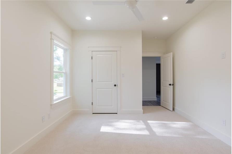 This bedroom has carpet flooring, white walls, and a framed window that invites natural light in.