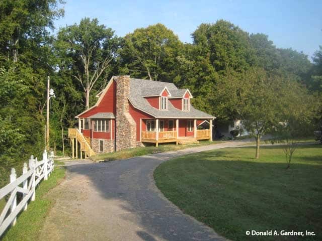 View of the house from afar showing its red siding, stone accents, and gable rooflines.