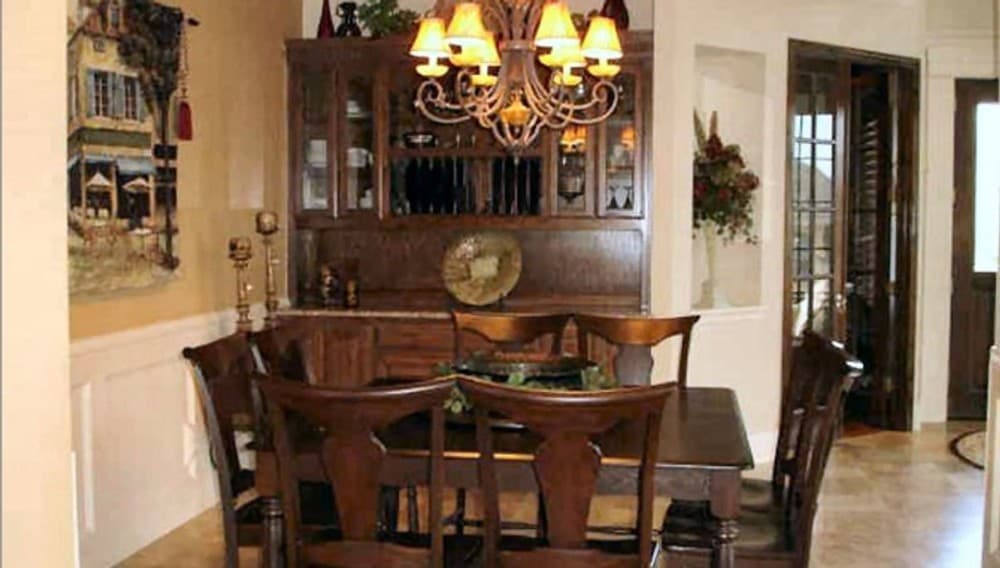 Formal dining room with built-in cabinets and a matching wooden dining set illuminated with a warm chandelier.