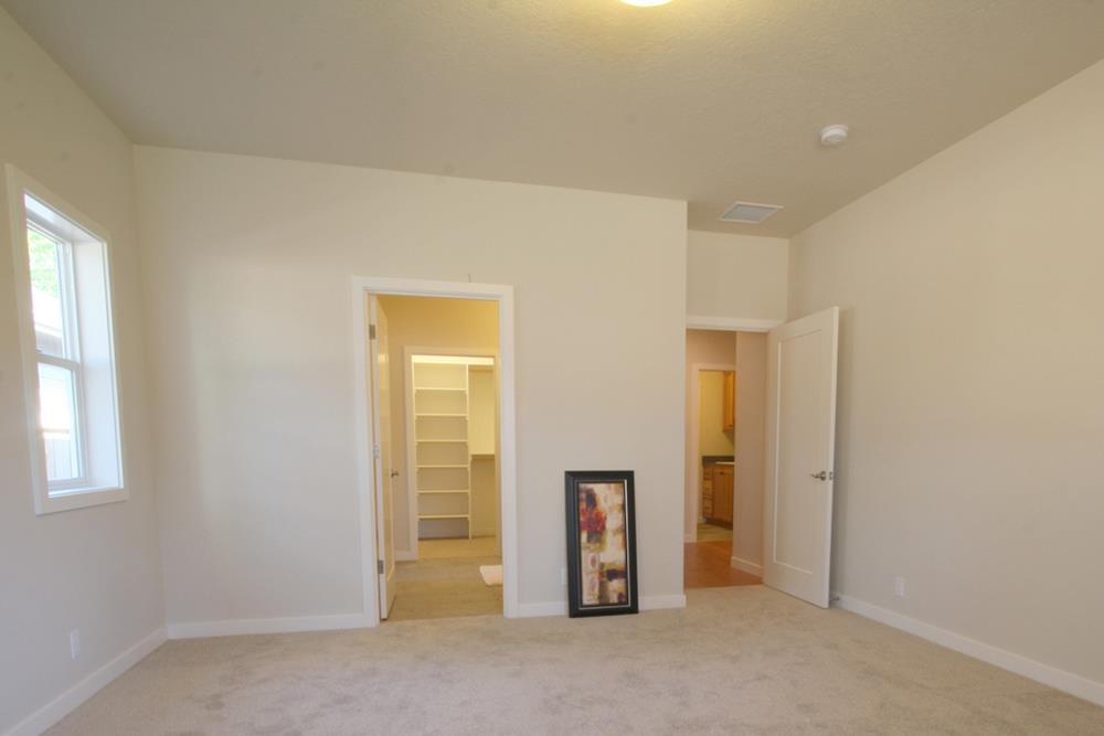 The primary bedroom has beige walls, carpet flooring, and a private bathroom.