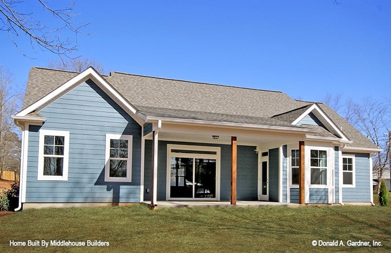 Rear exterior view with blue horizontal siding and a covered porch lined with rustic columns.