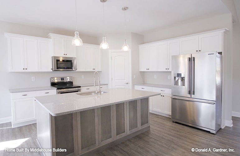 The kitchen is equipped with stainless steel appliances, white cabinetry, a corner pantry, and a breakfast island fitted with a sink.