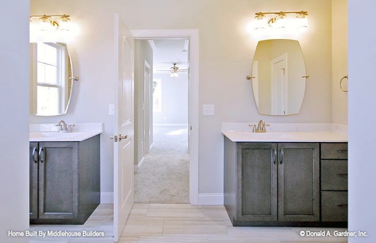 The primary bathroom features his and her sink vanities topped with frameless mirrors and glass sconces.