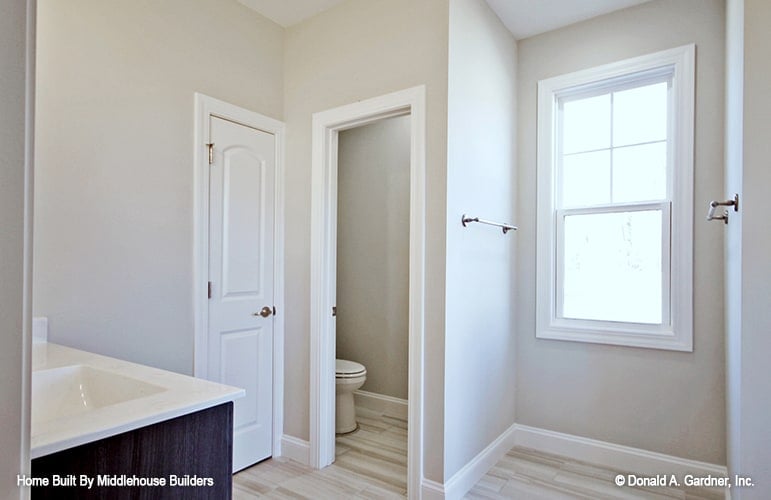 A toilet room and a white framed window complete the primary bathroom.