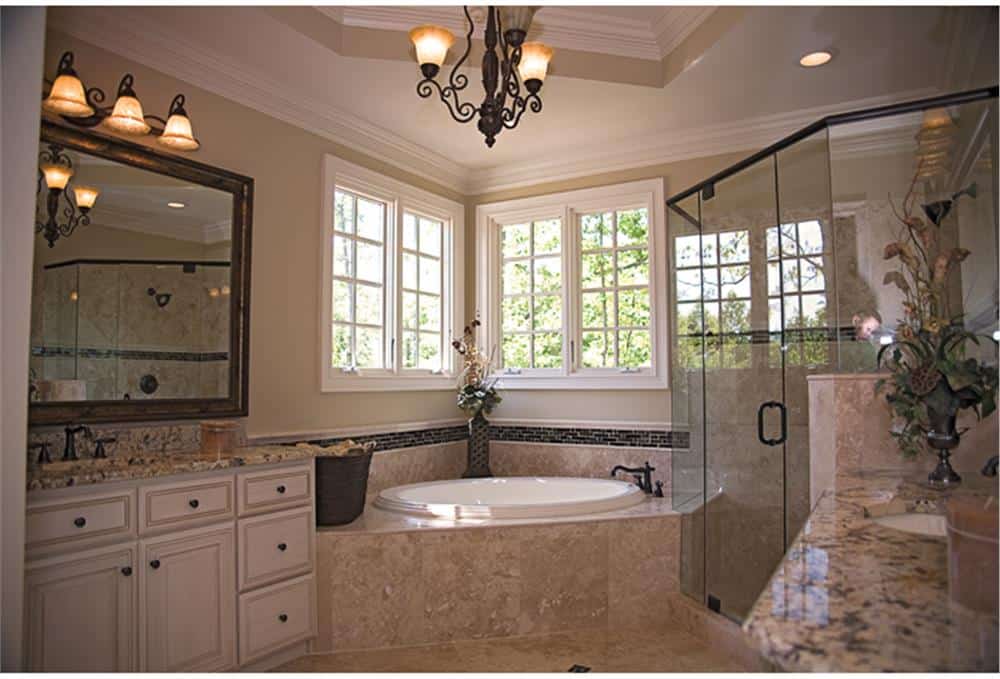 The primary bathroom is equipped with a large vanity, a walk-in shower, and a drop-in bathtub placed under the white-framed windows.