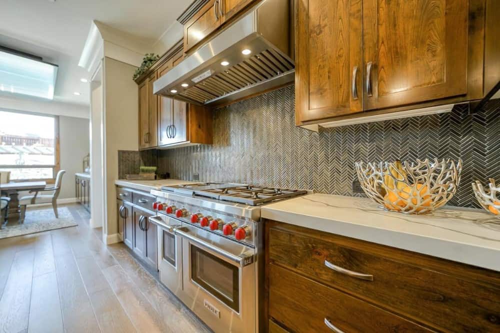 Double oven gas range and herringbone tile backsplash complete the kitchen.