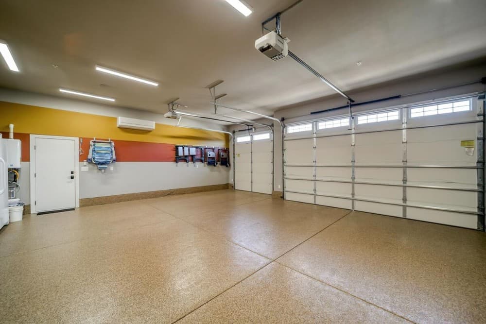 An oversized 3-car garage with tile flooring, multicolored walls, and linear ceiling lamps.