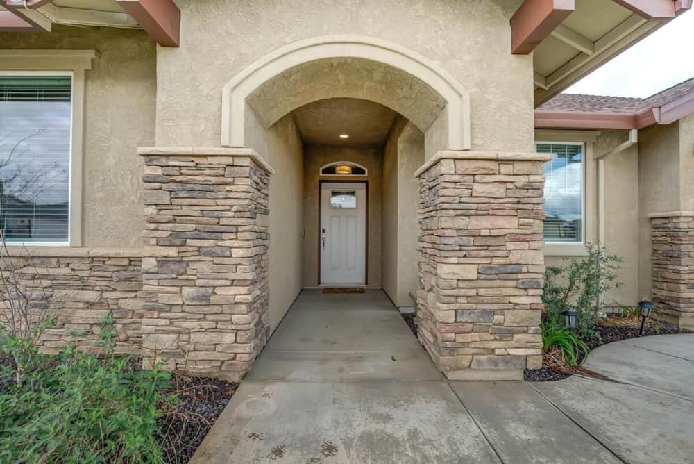 A closer look at the home entry with a stone archway and a white front door topped with an arched transom.