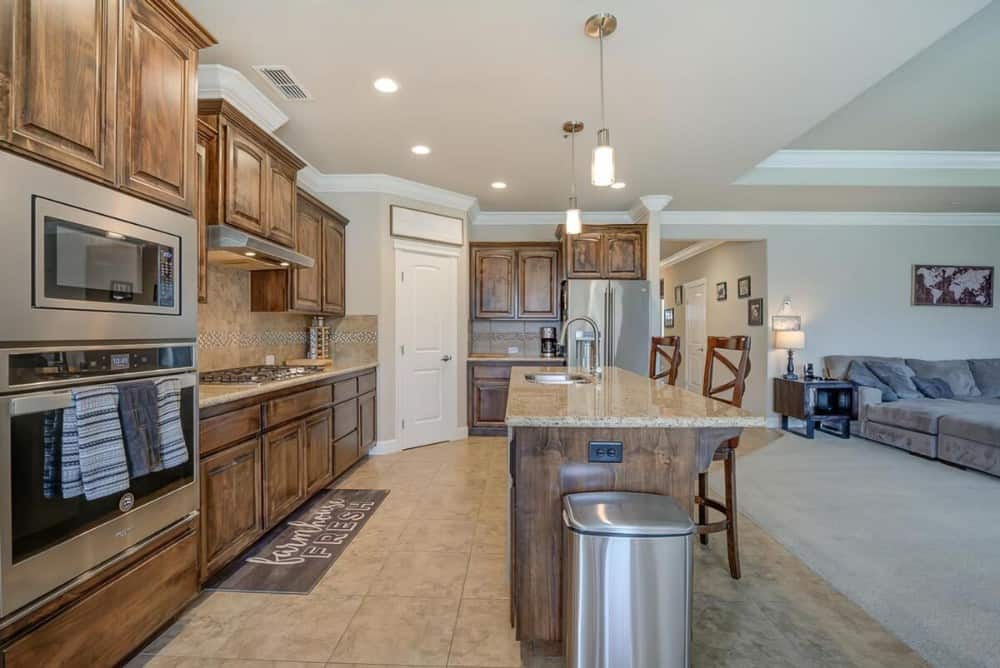 Kitchen with natural wood cabinetry, stainless steel appliances, and a breakfast island fitted with double sinks.