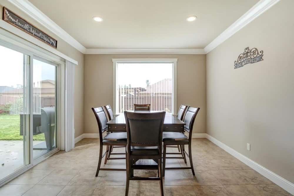 Dining nook with limestone flooring, a 6-seater dining set, and sliding glass doors leading to the rear patio.