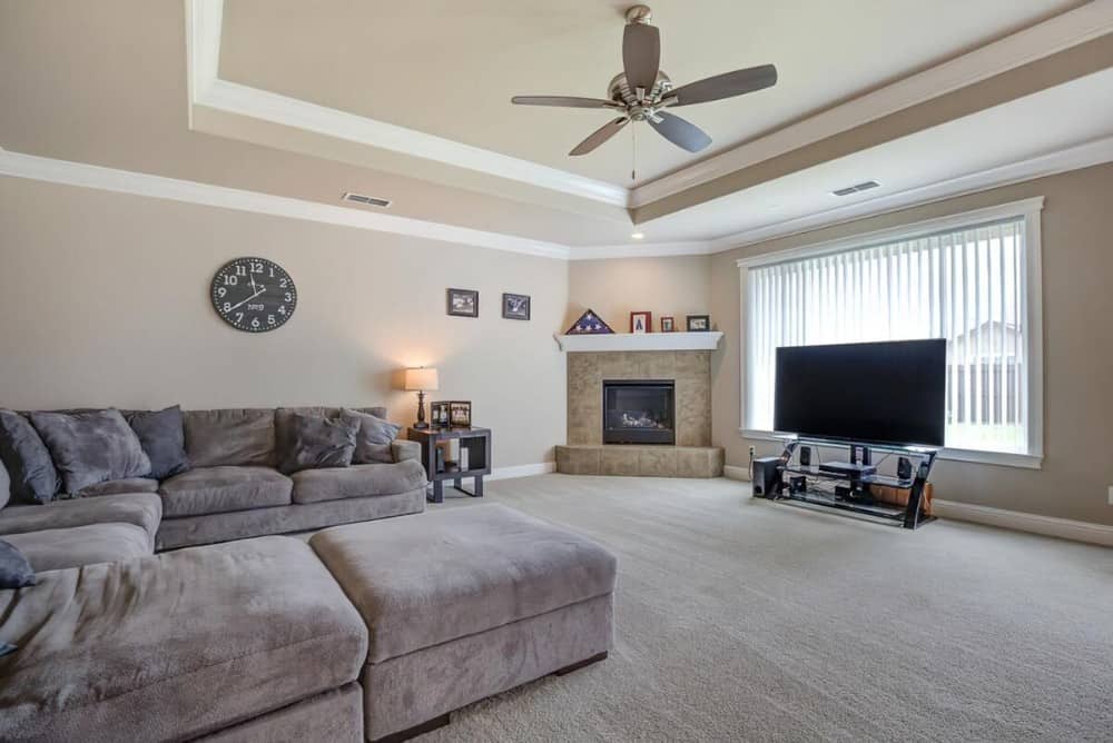 The great room includes a corner fireplace and a TV placed against the large window.