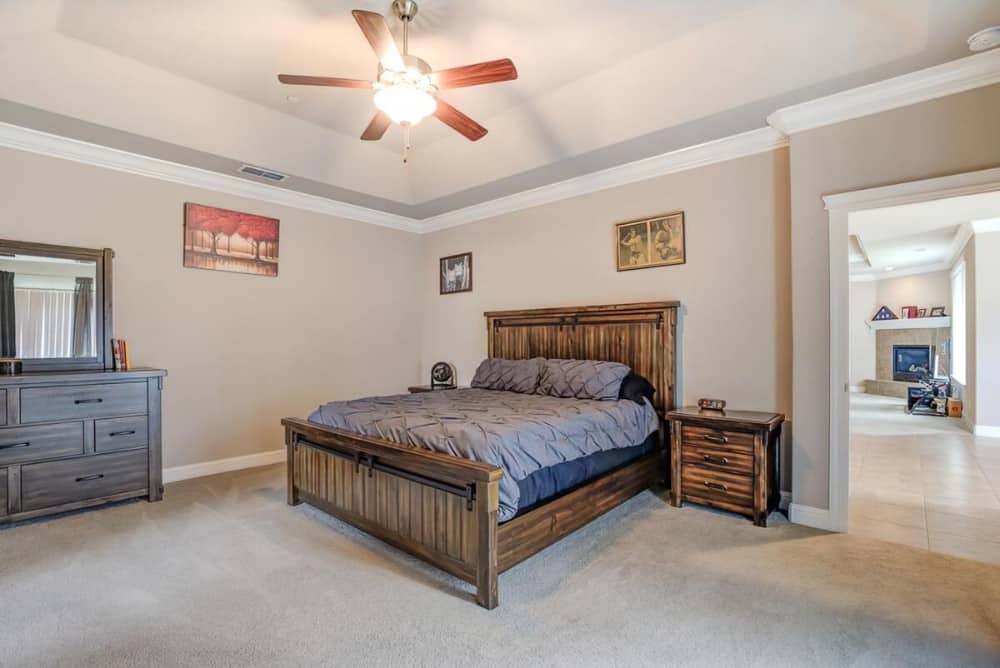 Primary bedroom with a coved ceiling, a distressed dresser, and a wooden bed flanked by matching nightstands.