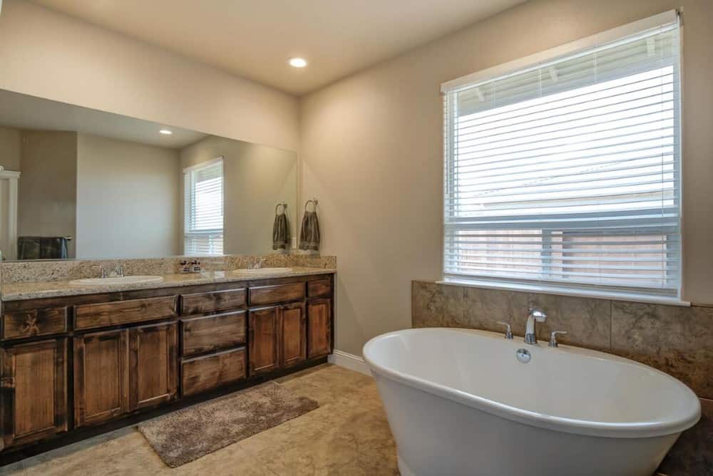 Primary bathroom with a freestanding tub and a dual sink vanity topped with a large frameless mirror.