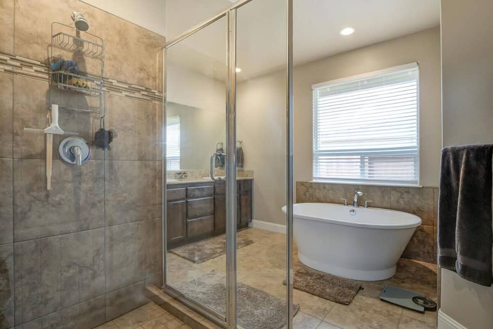 The walk-in shower has marble tile walls, sliding glass doors, and chrome fixtures.