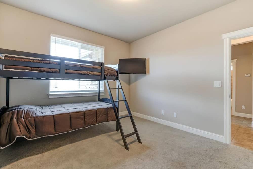 This bedroom offers a wall-mounted TV and a bunk bed over carpet flooring.