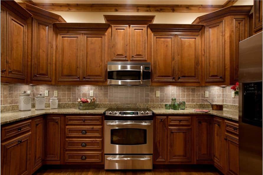 A closer look at the stainless steel cooking range and oven nestled between the wooden cabinetry.