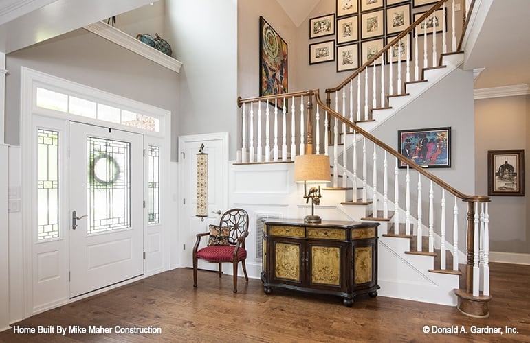 The foyer has a round-back chair and a traditional wooden console table topped with a drum table lamp.