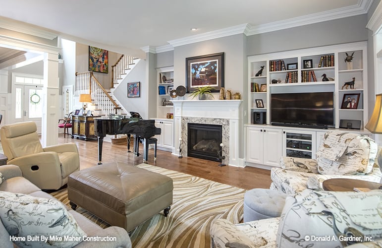 Great room with a gray sofa, leather recliner, patterned armchairs, and a fireplace flanked by white built-ins.