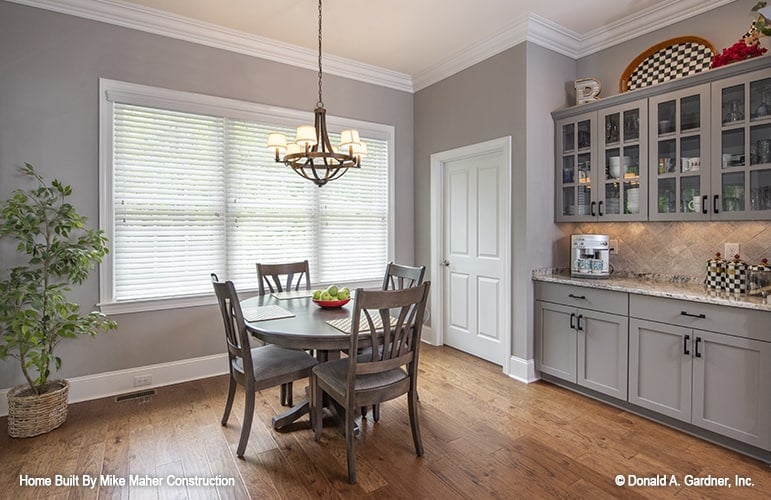 Breakfast nook with a built-in buffet cabinet and a round dining set topped with a warm chandelier.