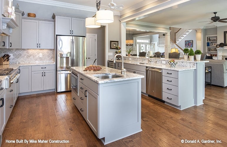 The kitchen offers gray cabinetry, stainless steel appliances, a center island, and a peninsula with a raised eating bar.