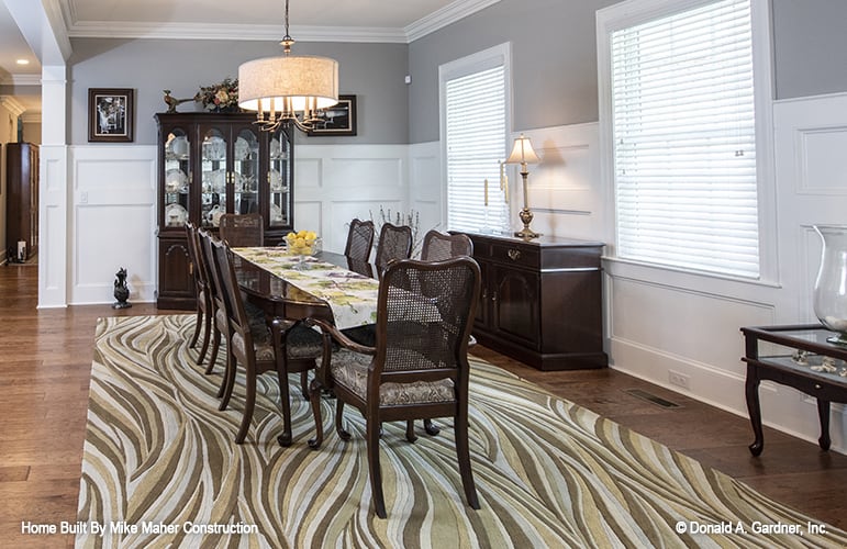 Formal dining room with a display cabinet, a dark wood buffet table, and a matching 8-seater dining set sitting on a large patterned rug.
