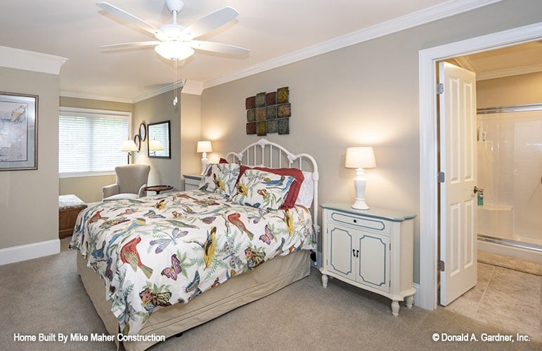 This bedroom offers a white metal bed and a small sitting area by the window.