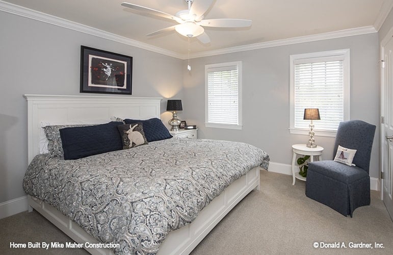 Bedroom with carpet flooring, a white bed, and a skirted chair paired with a round side table.