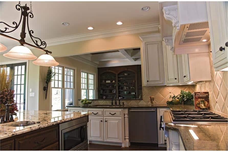 Kitchen with white cabinetry, granite countertops, a built-in cooktop, and a center island.