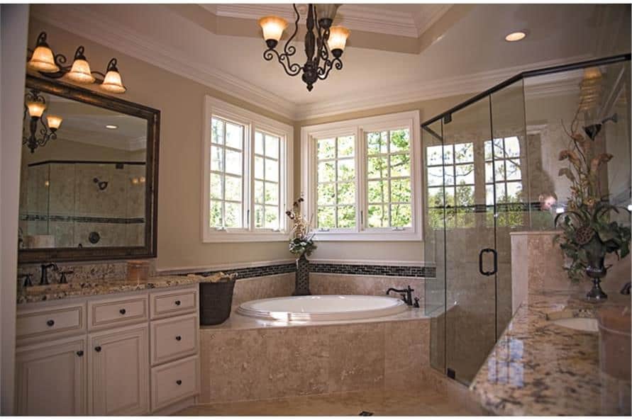 The primary bathroom is equipped with his and her sink vanities, a corner bathtub, and a walk-in shower.