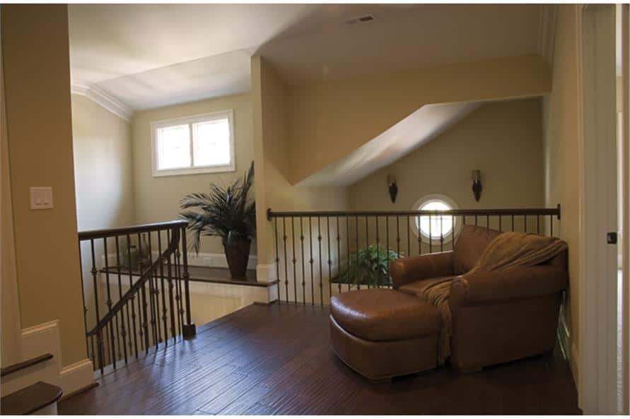 Balcony loft with a leather lounge chair and wrought iron railings overlooking the foyer below.