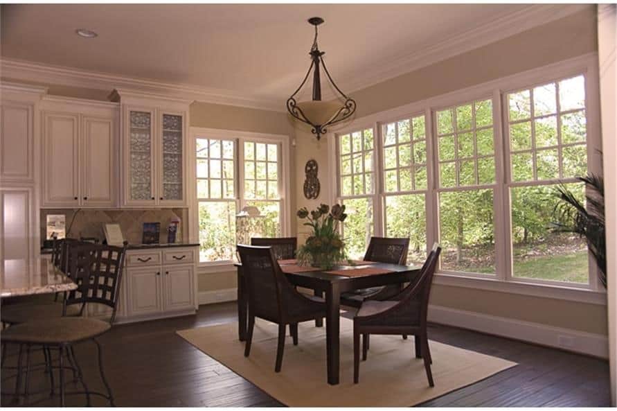 Breakfast nook with surrounding windows and 4-seater dining set sitting on a beige area rug.